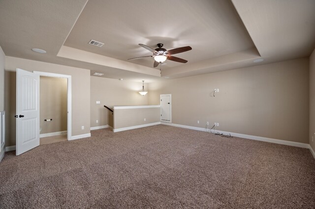 unfurnished room featuring a raised ceiling, ceiling fan, and carpet floors