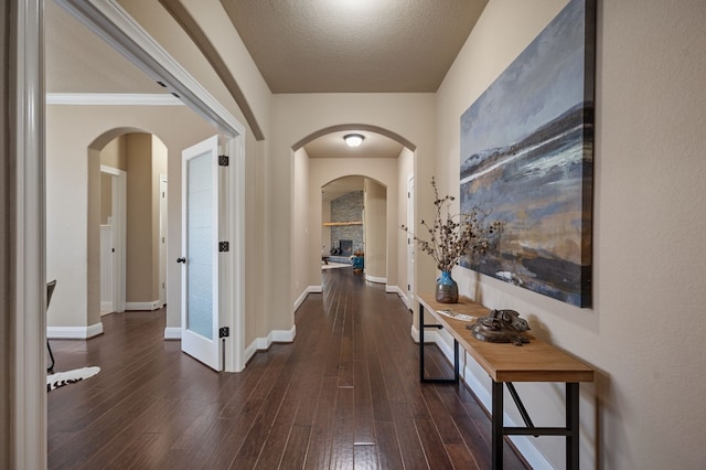 corridor featuring a textured ceiling, dark hardwood / wood-style flooring, and crown molding