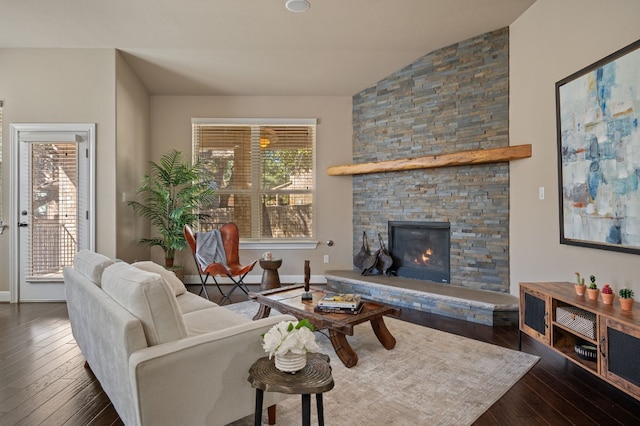 living room with dark hardwood / wood-style floors, vaulted ceiling, plenty of natural light, and a stone fireplace