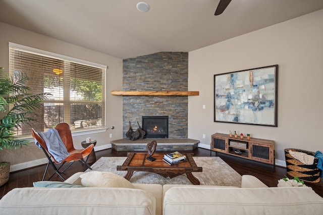 living room featuring dark hardwood / wood-style flooring, ceiling fan, a stone fireplace, and lofted ceiling