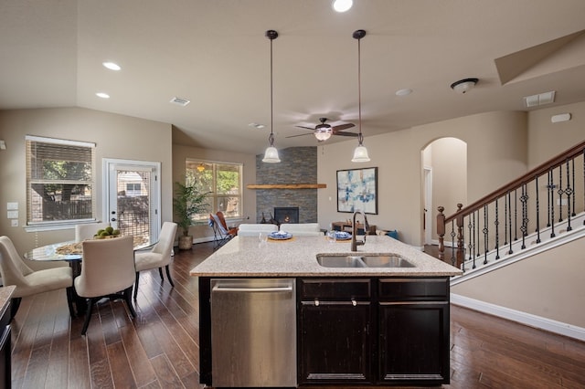 kitchen with dishwasher, sink, decorative light fixtures, a fireplace, and a center island with sink