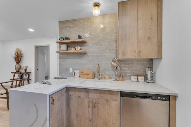 kitchen featuring light stone countertops, decorative backsplash, kitchen peninsula, stainless steel dishwasher, and sink