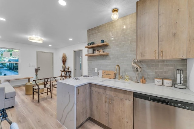 kitchen featuring backsplash, sink, light hardwood / wood-style flooring, stainless steel dishwasher, and light stone countertops