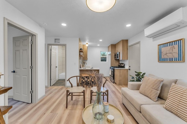 living room with a wall mounted air conditioner, light hardwood / wood-style floors, and sink