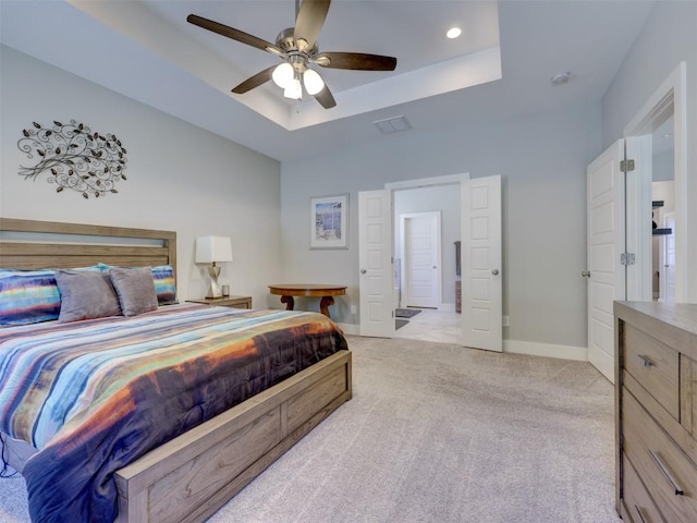 carpeted bedroom with a tray ceiling and ceiling fan