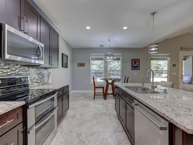 kitchen with tasteful backsplash, a wealth of natural light, stainless steel appliances, sink, and hanging light fixtures