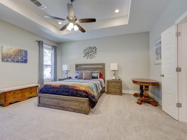 bedroom featuring light carpet, a tray ceiling, and ceiling fan