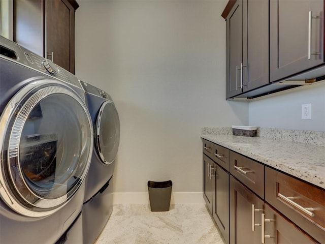 clothes washing area featuring washing machine and dryer and cabinets