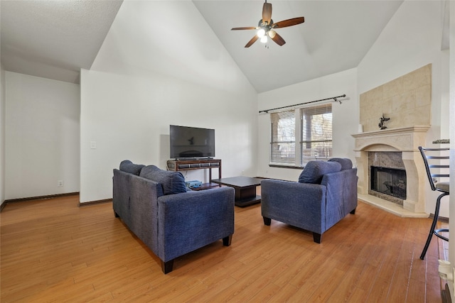 living room with a fireplace, hardwood / wood-style flooring, high vaulted ceiling, and ceiling fan