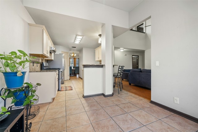 kitchen featuring white cabinetry, stainless steel range with gas cooktop, a notable chandelier, and light tile patterned flooring