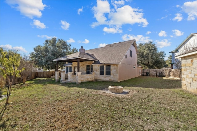 back of house with a yard and a fire pit