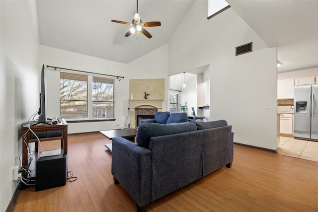 living room featuring ceiling fan, high vaulted ceiling, and light hardwood / wood-style floors