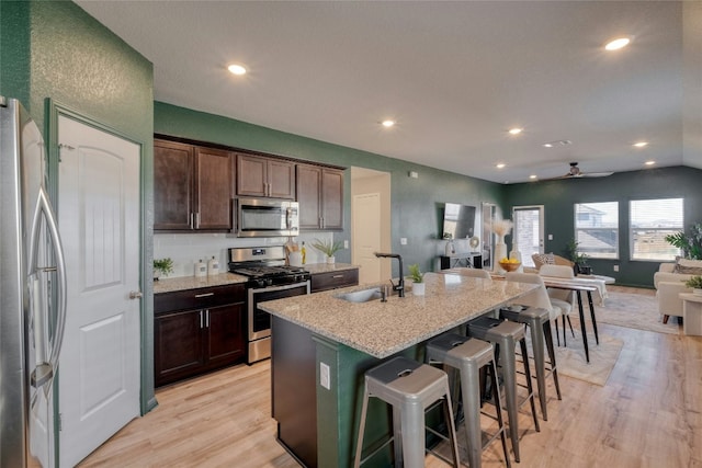 kitchen featuring a breakfast bar, sink, ceiling fan, an island with sink, and appliances with stainless steel finishes