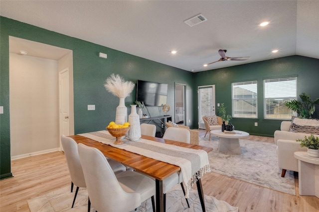 dining room featuring light wood-type flooring, vaulted ceiling, and ceiling fan