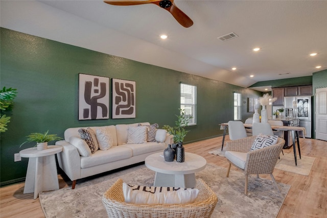 living room featuring lofted ceiling, ceiling fan, and light wood-type flooring