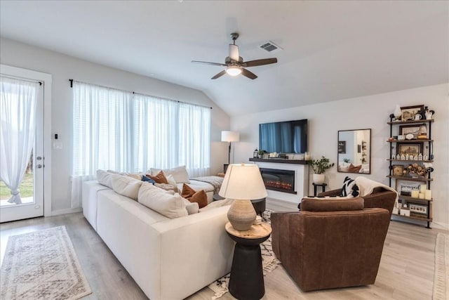 living room featuring ceiling fan, light hardwood / wood-style floors, and lofted ceiling