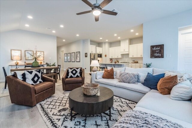 living room featuring lofted ceiling, ceiling fan, and light wood-type flooring