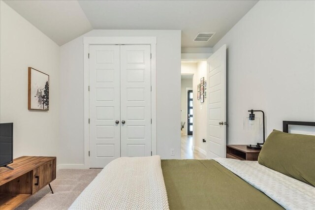 carpeted bedroom with lofted ceiling and a closet