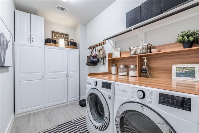 laundry area with washing machine and clothes dryer and cabinets