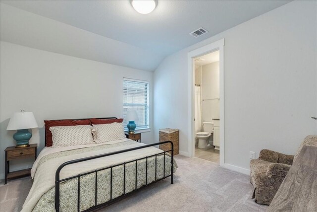 carpeted bedroom featuring connected bathroom and lofted ceiling