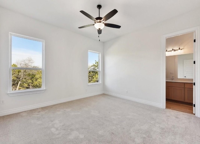 unfurnished bedroom featuring ensuite bathroom, ceiling fan, and light carpet