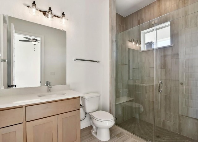 bathroom with vanity, toilet, ceiling fan, and a shower with shower door