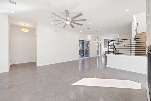 unfurnished room with ceiling fan with notable chandelier and concrete floors