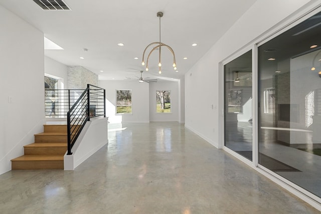 hall with concrete flooring and a chandelier