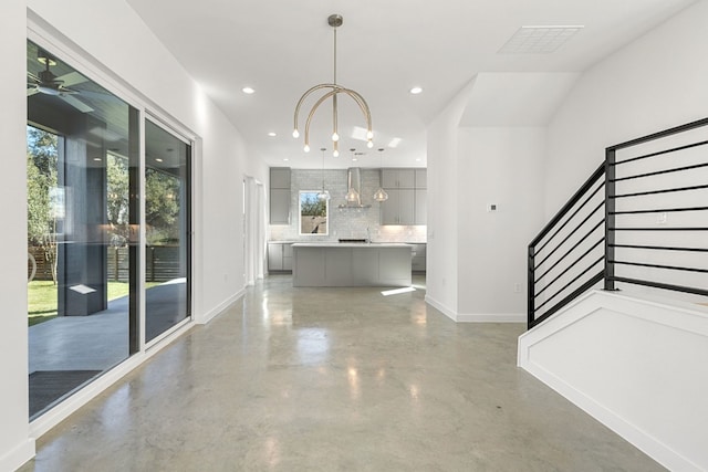 hallway with concrete flooring, vaulted ceiling, and a notable chandelier