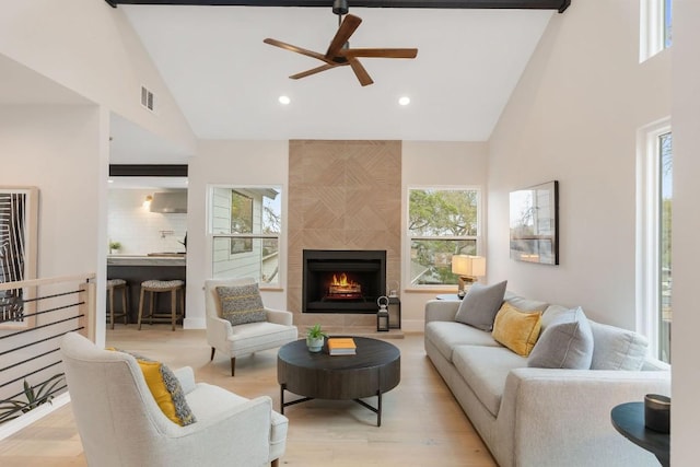 living room featuring ceiling fan, a fireplace, high vaulted ceiling, and light hardwood / wood-style floors