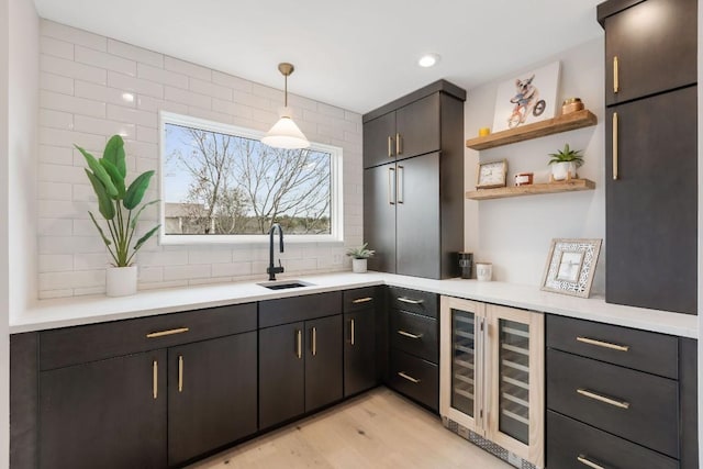 kitchen with sink, beverage cooler, light hardwood / wood-style flooring, pendant lighting, and decorative backsplash