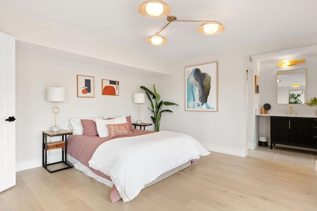 bedroom with connected bathroom and light hardwood / wood-style floors