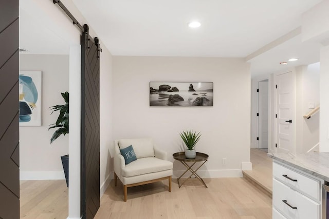 living area with a barn door and light hardwood / wood-style flooring