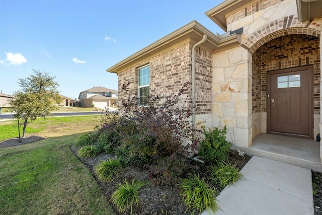 view of exterior entry featuring a lawn