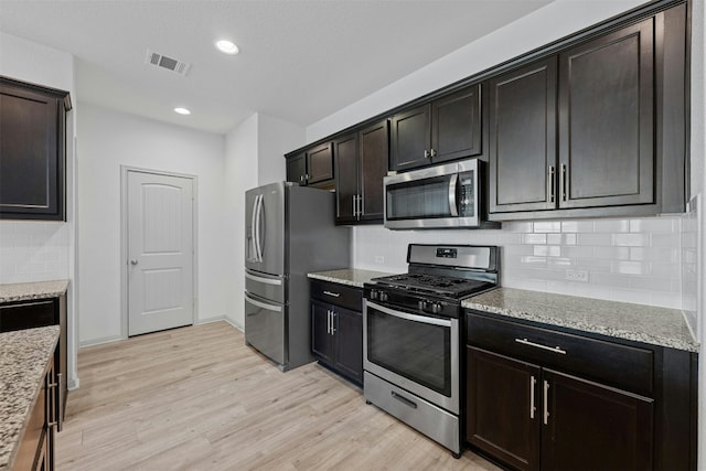 kitchen featuring backsplash, dark brown cabinetry, light hardwood / wood-style flooring, and appliances with stainless steel finishes