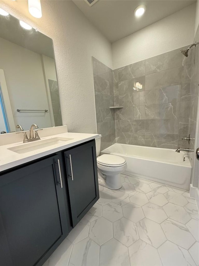 full bath with toilet, marble finish floor, washtub / shower combination, vanity, and a textured wall