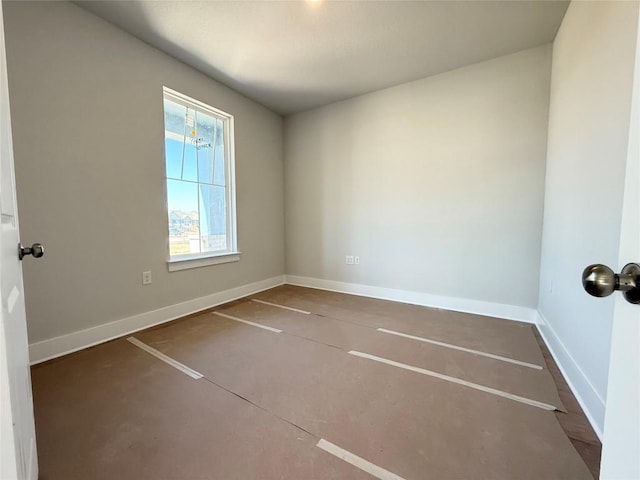 unfurnished room featuring concrete floors and baseboards