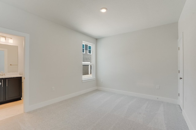 8504 Dongan Dr, Austin, TX 78744 - unfurnished bedroom featuring light colored carpet, baseboards, ensuite bath, and a sink