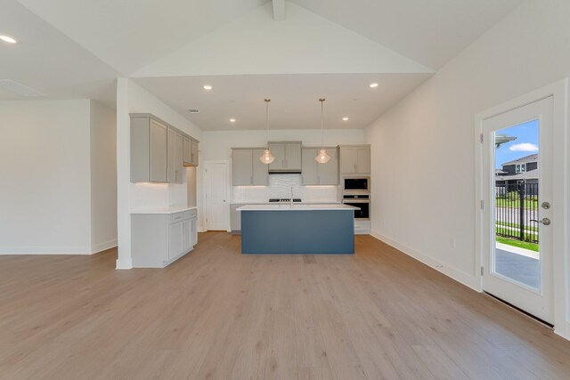 8504 Dongan Dr, Austin, TX 78744 - kitchen with stainless steel oven, built in microwave, gray cabinets, light wood-style floors, and backsplash