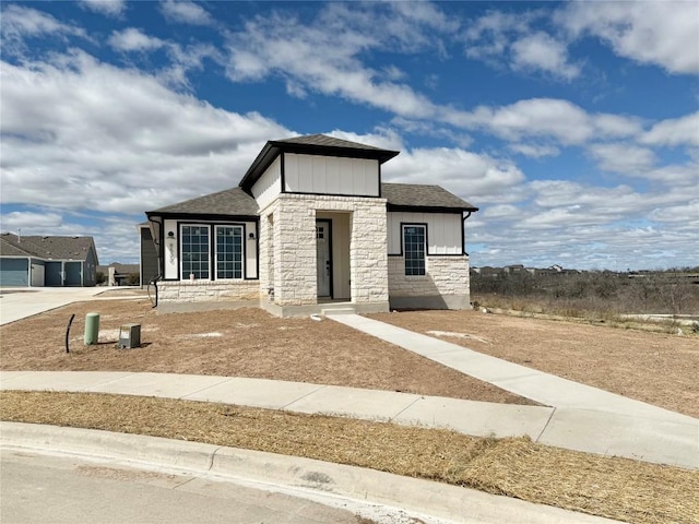 view of front of house with concrete driveway, stone siding, and a shingled roof