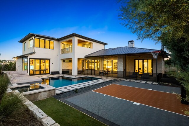 back of property featuring a patio area and a pool with hot tub