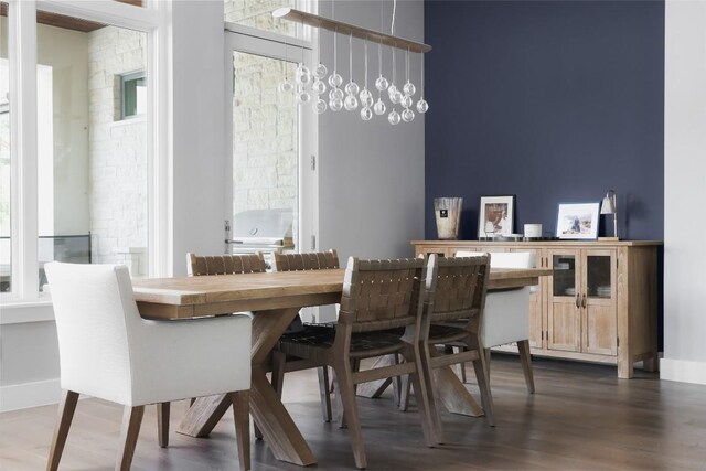 dining area with a chandelier, a wealth of natural light, and dark wood-type flooring