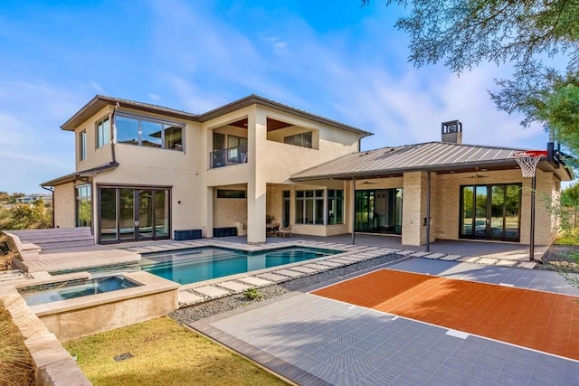 rear view of property featuring a patio area, ceiling fan, and a pool with hot tub