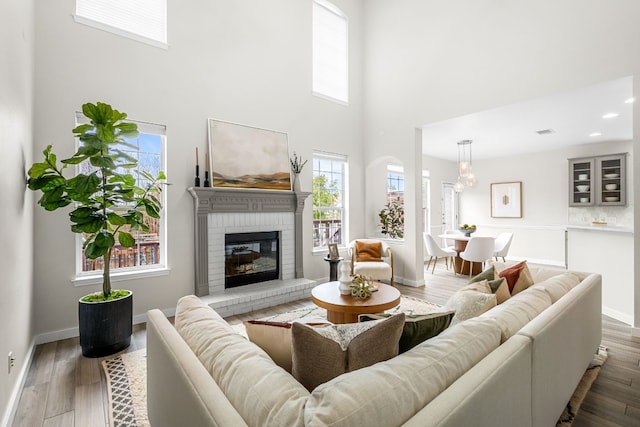 living room with a towering ceiling, dark wood-type flooring, and a brick fireplace