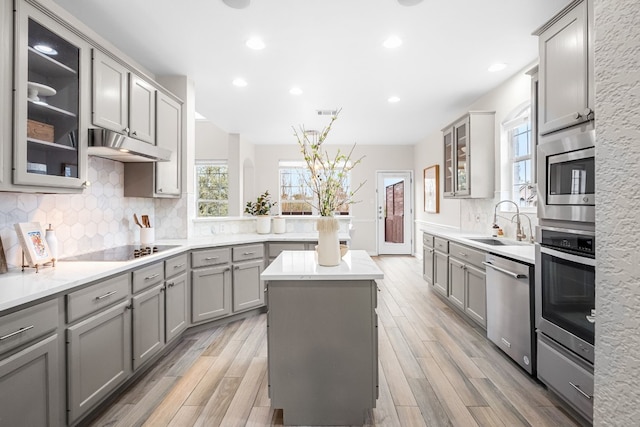 kitchen featuring a center island, sink, decorative backsplash, gray cabinets, and stainless steel appliances