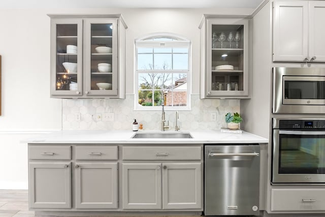 kitchen featuring decorative backsplash, appliances with stainless steel finishes, gray cabinetry, and sink