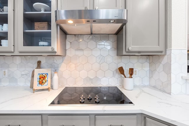 kitchen featuring decorative backsplash, black electric cooktop, light stone countertops, and exhaust hood