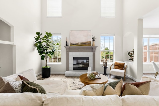 living room with a fireplace, a high ceiling, and light wood-type flooring