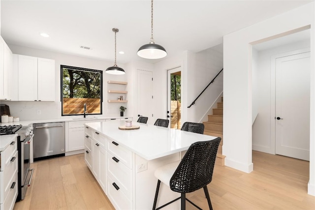 kitchen featuring white cabinets, a kitchen island, stainless steel appliances, and a breakfast bar area