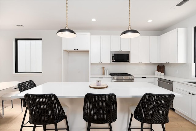 kitchen featuring appliances with stainless steel finishes, a kitchen island, white cabinetry, and pendant lighting